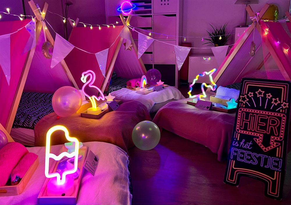 Tipi&rsquo;s met neonlampjes en een bord &lsquo;Hier is het feestje&rsquo;