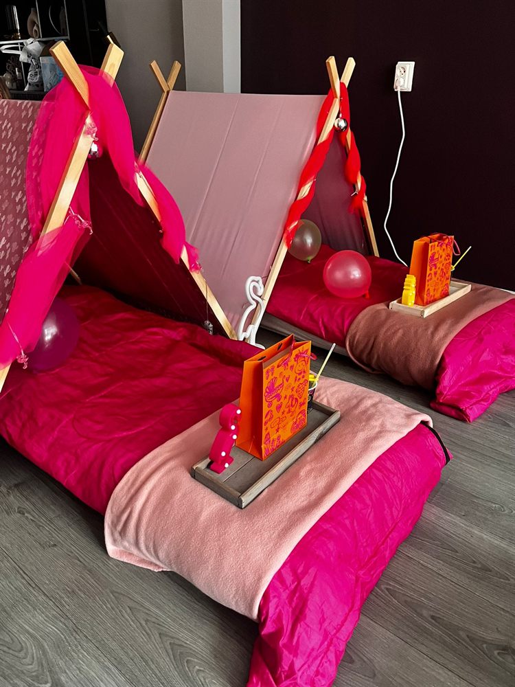 Twee roze tipi&rsquo;s met ballonnen en een traktatiezakje op een dienblad
